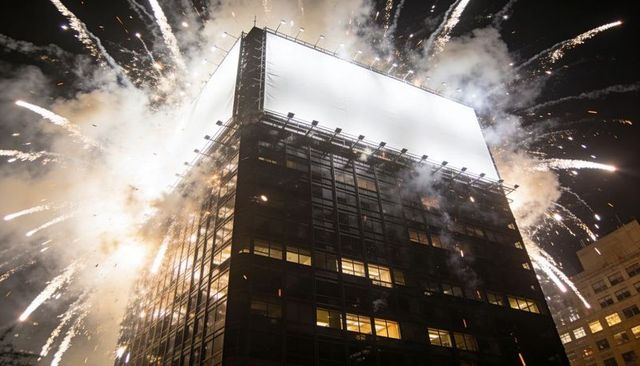 Rooftop Billboard Erupting with Fireworks Above High-Rise Night Skyline Urban Celebration