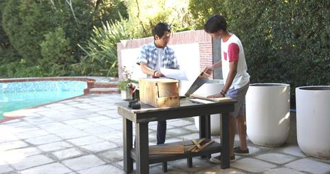 Father and son assembling wood frame on patio workbench