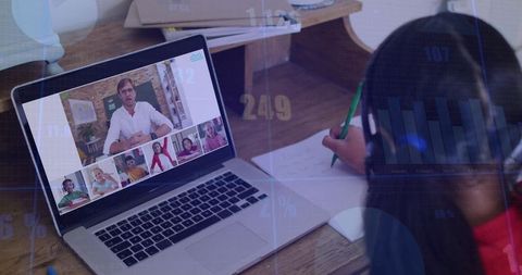 Child Writing During Live Online Class Using Laptop and Headphones at Desk with Green Pencil