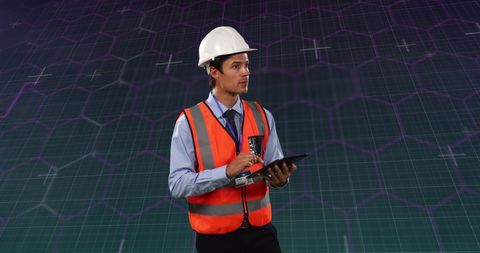 Engineer in safety gear analyzing financial data on digital tablet