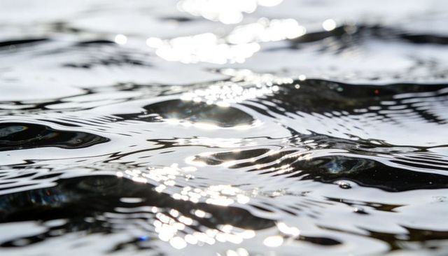 Shimmering ripples on lake surface reflecting sunlight, abstract water texture and motion