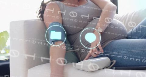 Pregnant woman using home blood pressure monitor with holographic telehealth interface cuff
