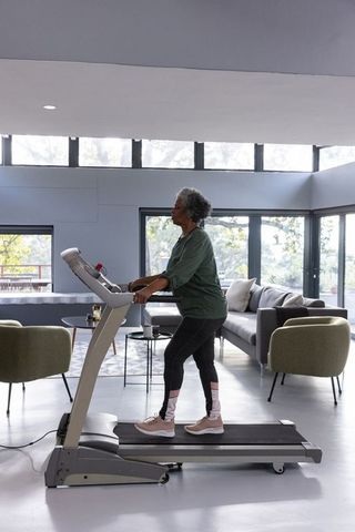 Senior Woman Walking on Treadmill in Stylish Living Room