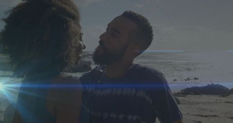 Couple Embracing on Backlit Rocky Beach with Sun Flare and Ocean Horizon, Silhouette