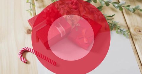 Displaying red gift boxes with ribbons on light wood tabletop with candy cane and blank card