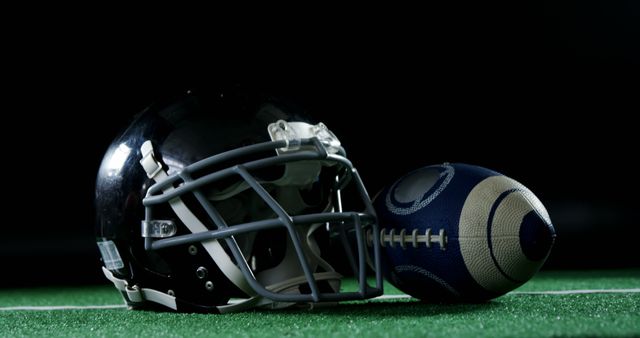 Football Helmet and Ball on Green Field under Dramatic Lighting - Download Free Stock Images Pikwizard.com