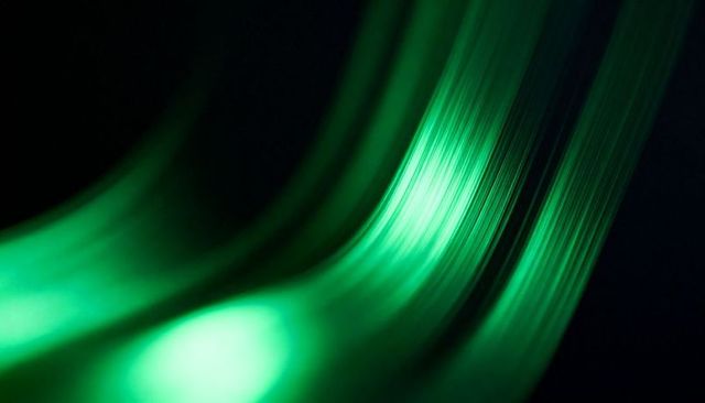 Luminescent emerald filaments flowing diagonally with soft bokeh highlights