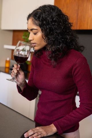 Woman Enjoying Red Wine Aroma in Modern Kitchen