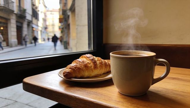 Steaming coffee mug and golden croissant on window table in city café morning