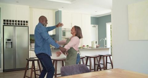 Mature African American Couple Embracing and Laughing in Modern Sunlit Kitchen