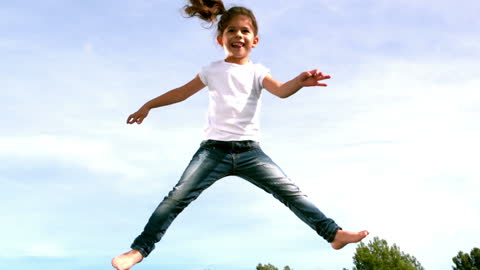 Child Joyfully Jumping on Trampoline Outdoors