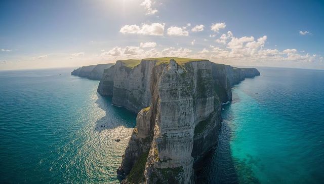 Towering chalk cliffs, turquoise sea aerial view, rugged coastal limestone headland