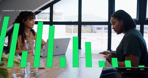 Coworkers reviewing reports and collaborating over laptop with analytics chart overlay