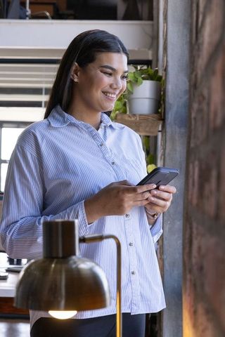 Professional Woman Using Smartphone in Modern Office Loft