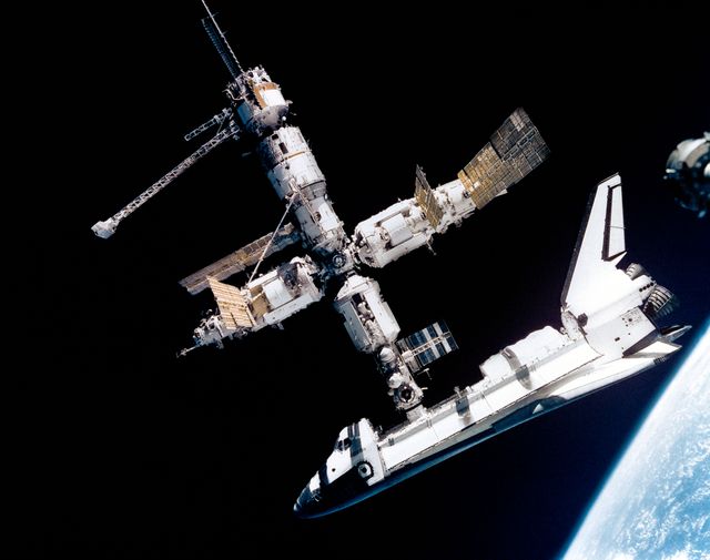 Space Shuttle Atlantis connected to Russia's Mir Space Station, photographed by Mir-19 crew on July 4, 1995. The image captures historical collaboration in space exploration by NASA and Russian cosmonauts. Suitable for educational materials on space history, joint-space missions, or scientific presentations about international collaboration in space.