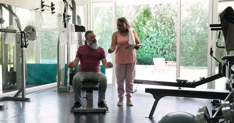 Senior Couple Exercising in Home Gym with Tablet Technology