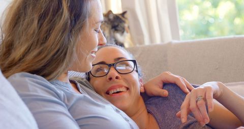 Two Women Relaxing Joyfully on Couch with Natural Light