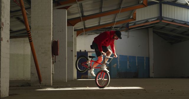 BMX Biker in Abandoned Warehouse Performing Stunt in Red Hoodie - Download Free Stock Images Pikwizard.com