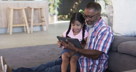 Grandfather Granddaughter Bonding with Tablet Technology at Home