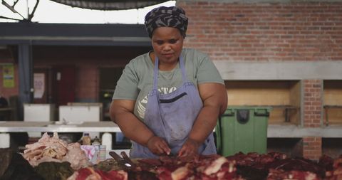 African female butcher preparing fresh meat in township workshop
