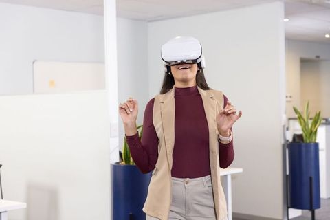 Businesswoman exploring virtual reality in modern office while wearing vr headset