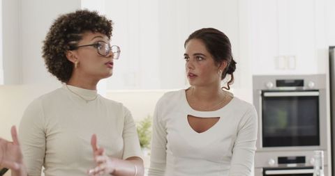 Women in kitchen preparing drinks in elegant outfits