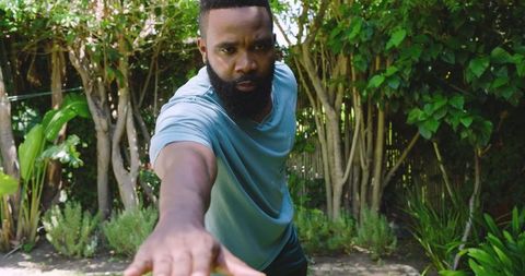 Mid Adult Man Reaching Hand Forward in Lush Backyard