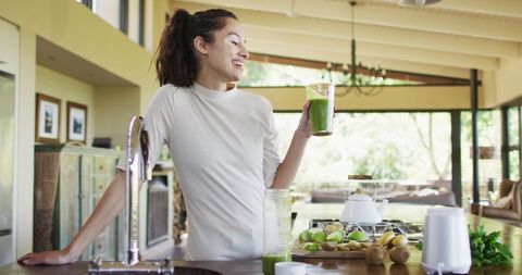 Woman Enjoying Green Smoothie in Bright Modern Kitchen