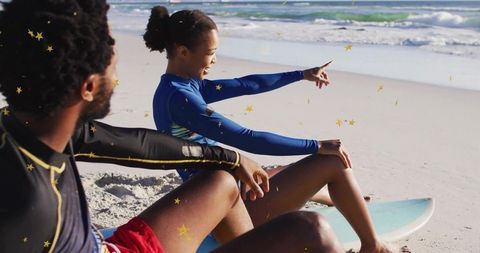 Surf Enthusiasts Relax on Sandy Beach Pointing at Ocean