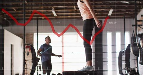 Woman performing plyo box step-up in industrial gym with jump rope partner and data overlay