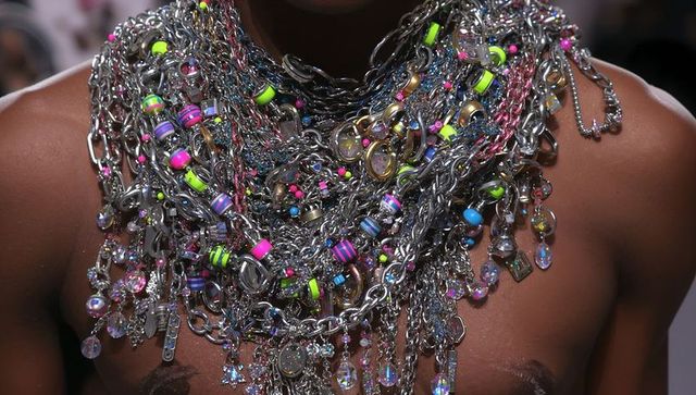 Layered metal chain necklaces with neon beads and crystal pendants on bare torso editorial