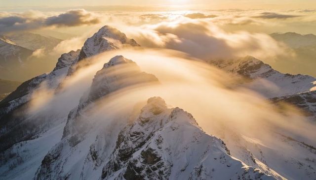 Alpenglow streaming over jagged snow-covered alpine ridge at sunrise