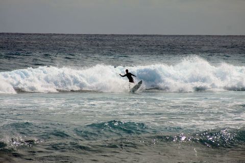 Surfer braving ocean waves at sunset