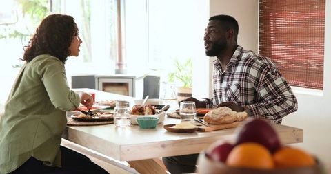 Couple Enjoying Meal Together at Home with Roast Chicken and Bread