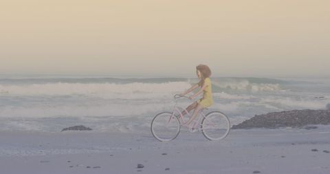 Woman Riding Bicycle Along Serene Beach Sunset