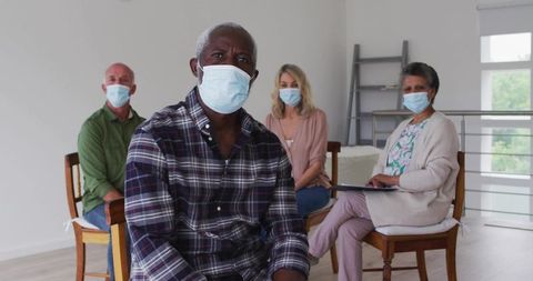 Mature adults wearing surgical masks attending support group session in bright clinic