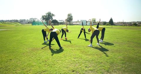 Diverse Team Stretching on Field for Fitness Warm-up