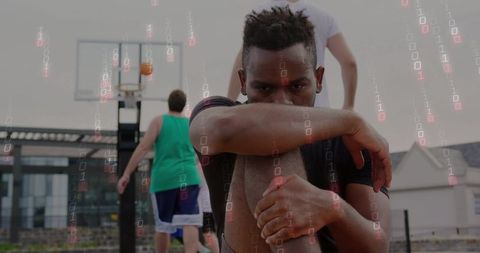 Sitting athlete gazing at camera on urban basketball court with binary code overlay