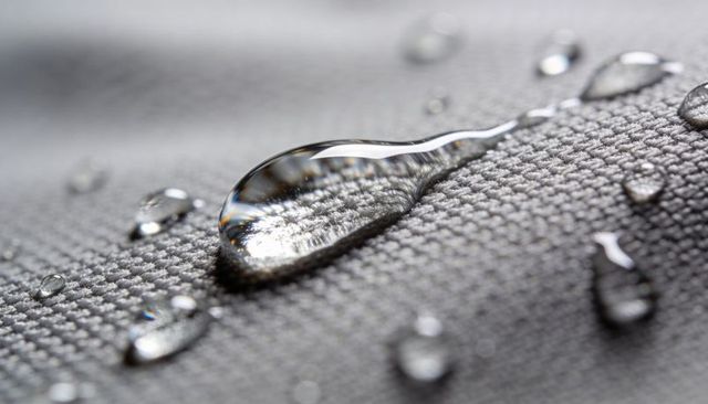 Macro water droplet beading on gray woven textile closeup fabric texture and reflections