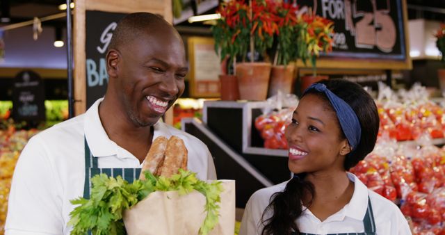 Smiling male and female grocery store workers holding fresh produce and bread. Ideal for illustrating concepts related to fresh food markets, customer service, teamwork in retail, and employee satisfaction.