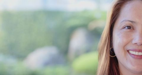 Smiling Mature Asian Woman with Hoop Earrings in Tranquil Garden