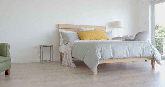 Modern minimalist bedroom featuring light wood furniture and cozy bedding. Ideal for promoting home decor, interior design inspiration, or lifestyle magazines. Bright and airy with clean lines and a peaceful ambiance.
