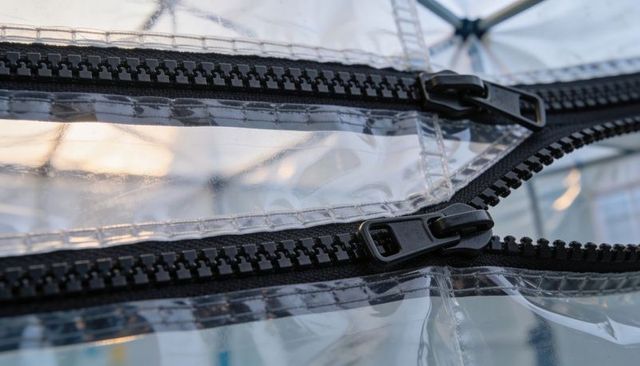 Close-up black zipper tracks sliders clear vinyl canopy highlighting industrial hardware