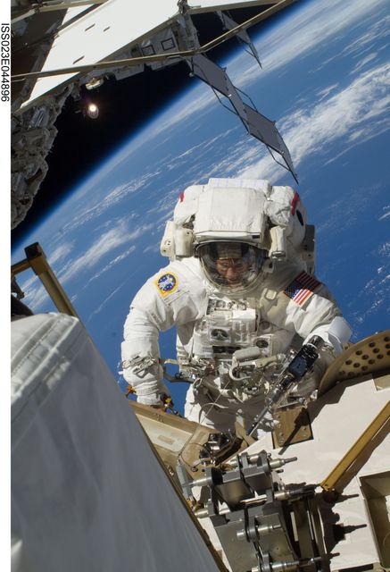 Astronaut Steven Bowen is captured during an extravehicular activity (EVA) on the International Space Station (ISS). He is wearing a white spacesuit and working outside the spacecraft with Earth visible in the background. This image could be used to illustrate space exploration, the duties of astronauts, or details about space station maintenance. Ideal for educational content, science presentations, or articles about NASA missions.
