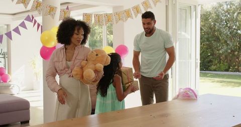 Family celebrating birthday at home with gifts and balloons