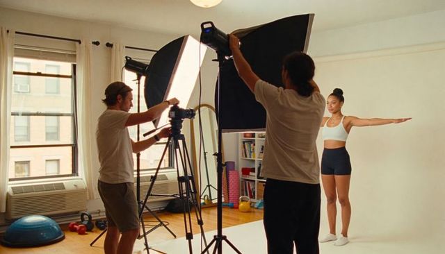 Fitness model posing with arms extended in apartment studio with dslr and softbox lighting