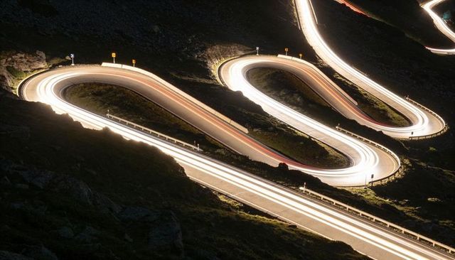 Winding alpine road light trails at night long exposure hairpin turns serpentine