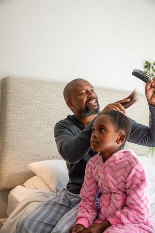 African american father brushing daughter hair during morning routine gentle family bonding