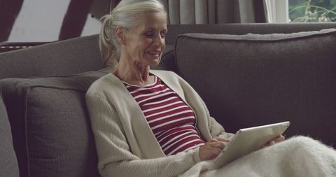 Senior Woman Comfortably Using Tablet in Cozy Living Room