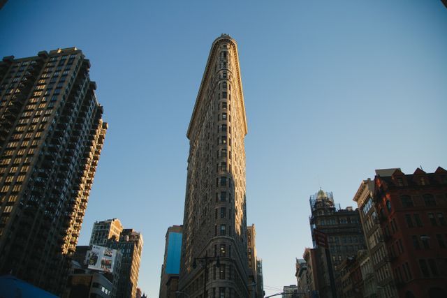 Image showcasing famous Flatiron Building in New York City, captured against clear blue sky. Suitable for use in travel blogs, architectural websites, tourism advertisements, and educational material focusing on historic landmarks and urban architectures.